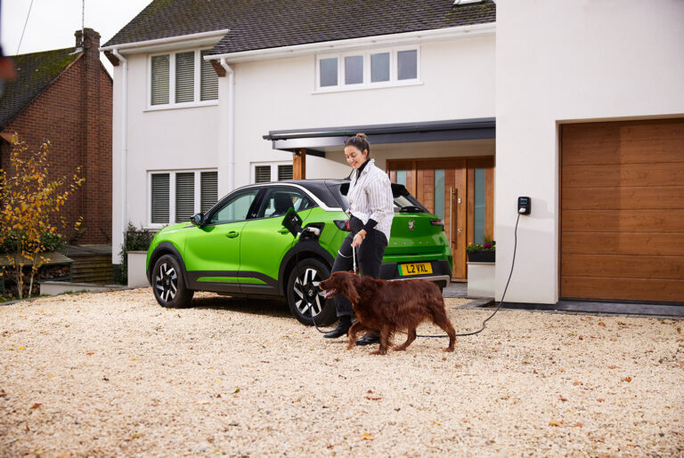 House with car on the drive being charged with woman and dog