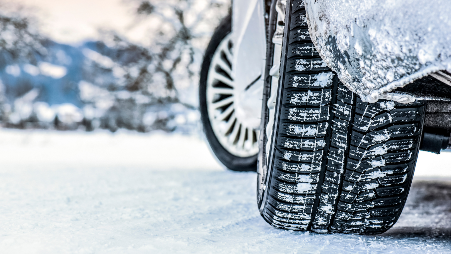 Tyre on a car overed in snowy on a snowy road.